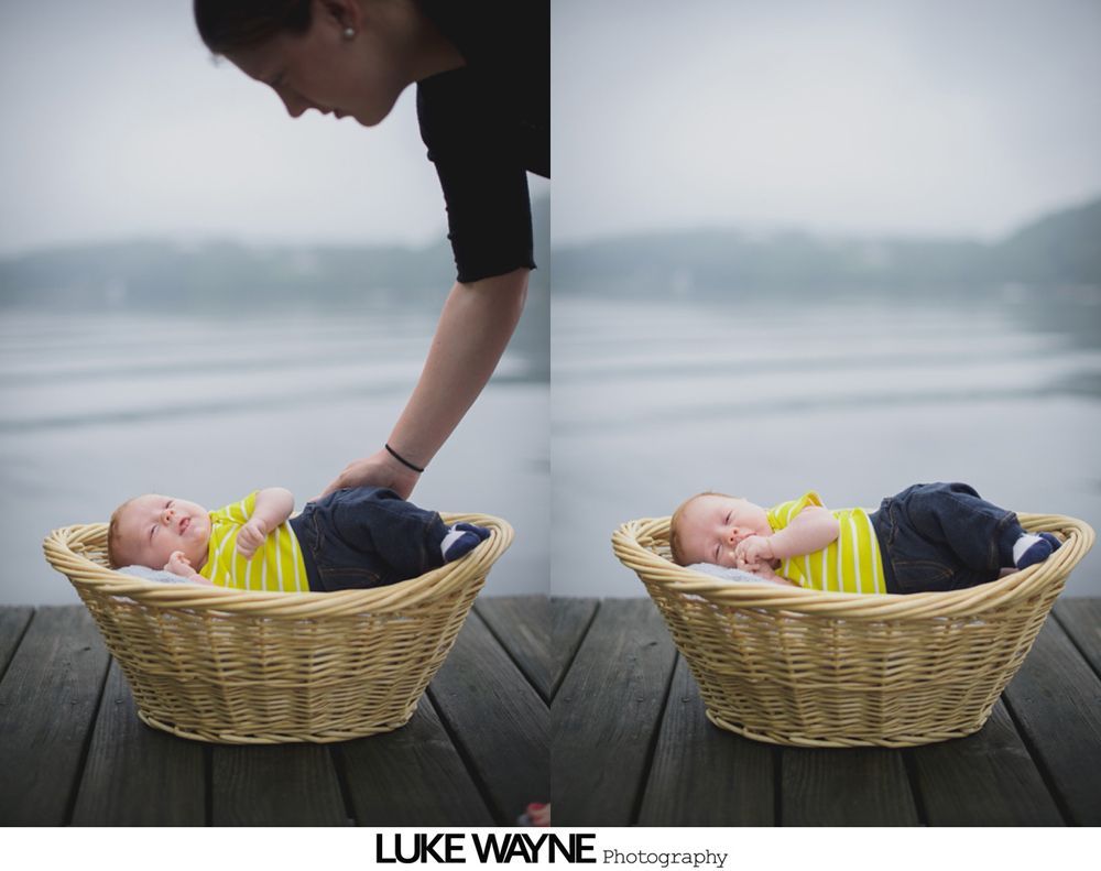 A baby in a wicker basket on a dock, person leaning over. Misty water in background.
