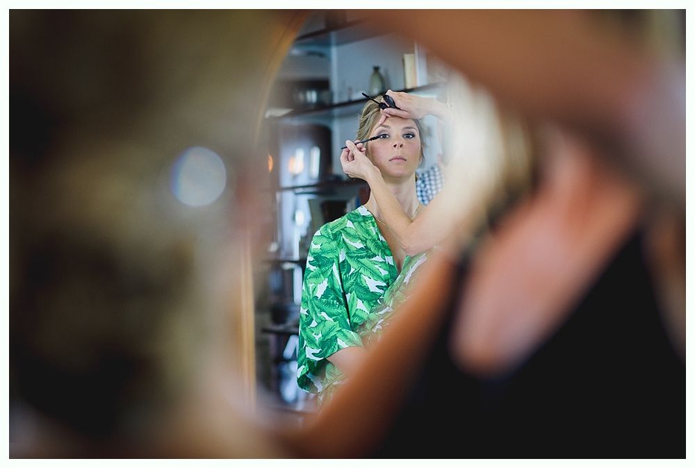 Bride with arms up, making a funny face, groom looking at his hand, cake cutting in background.