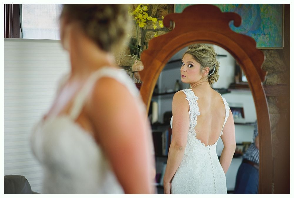 Bride with arms up, making a funny face, groom looking at his hand, cake cutting in background.