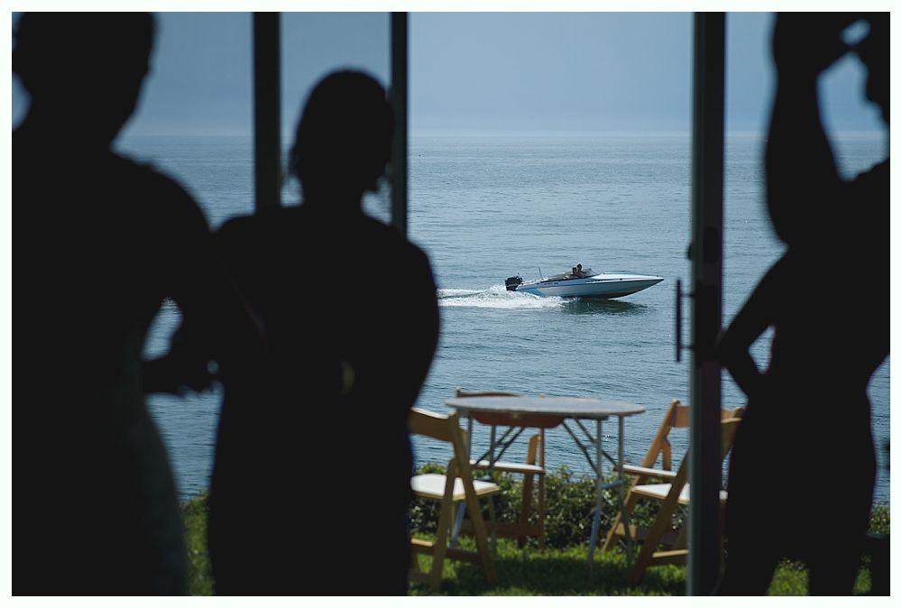 Bride with arms up, making a funny face, groom looking at his hand, cake cutting in background.