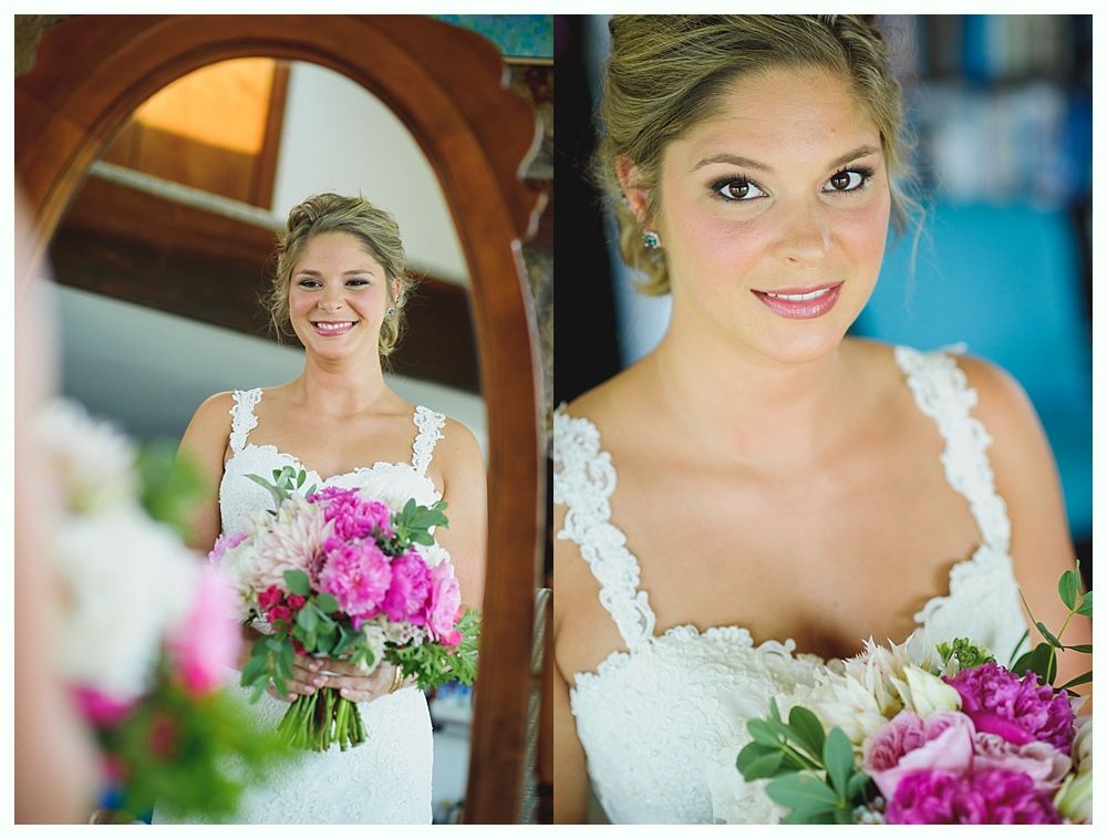 Bride with arms up, making a funny face, groom looking at his hand, cake cutting in background.