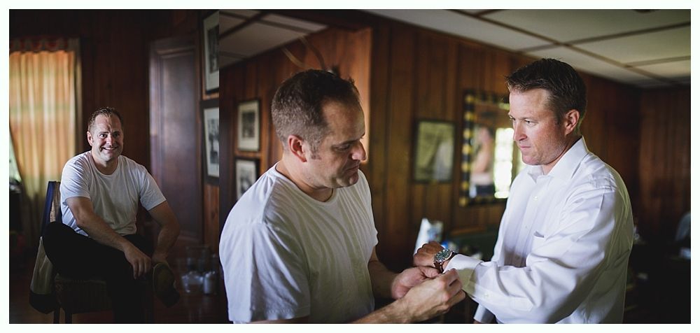 Bride with arms up, making a funny face, groom looking at his hand, cake cutting in background.