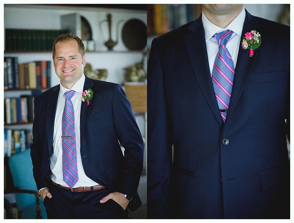 Bride with arms up, making a funny face, groom looking at his hand, cake cutting in background.