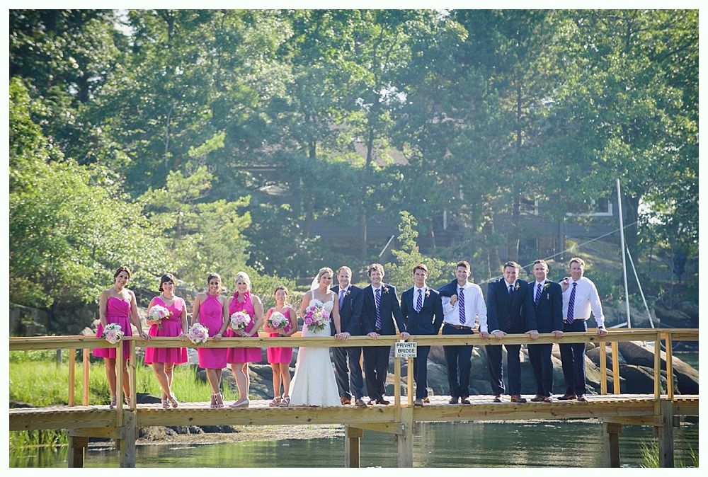 Bride with arms up, making a funny face, groom looking at his hand, cake cutting in background.