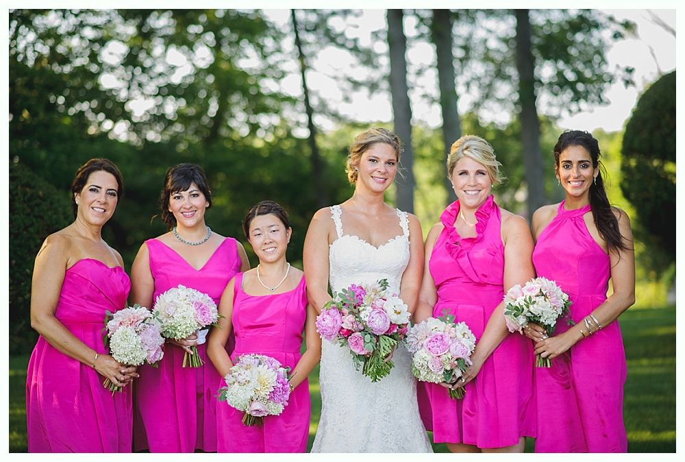 Bride with arms up, making a funny face, groom looking at his hand, cake cutting in background.