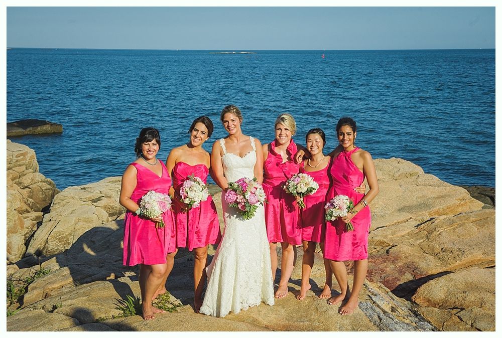 Bride with arms up, making a funny face, groom looking at his hand, cake cutting in background.