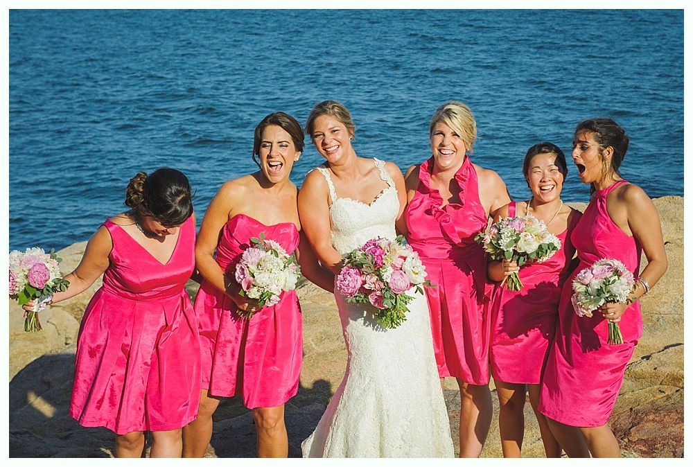 Bride with arms up, making a funny face, groom looking at his hand, cake cutting in background.