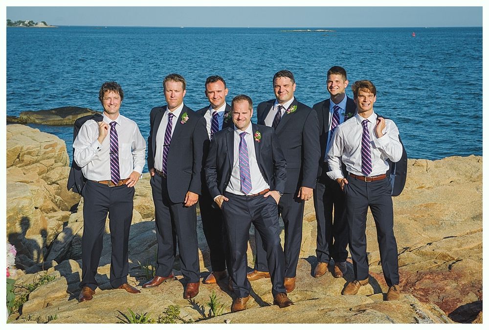 Bride with arms up, making a funny face, groom looking at his hand, cake cutting in background.