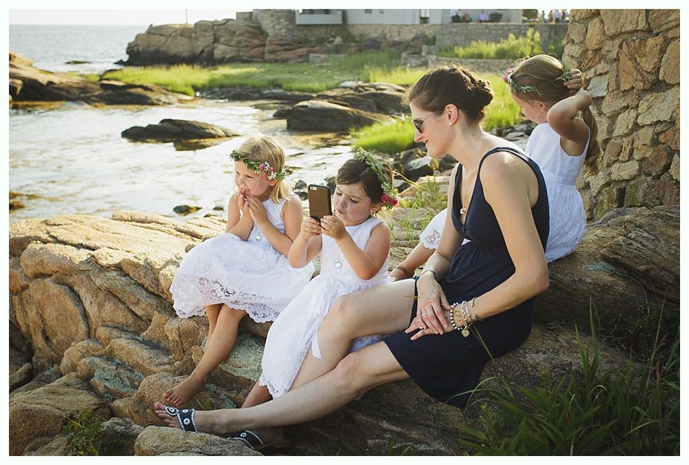 Bride with arms up, making a funny face, groom looking at his hand, cake cutting in background.