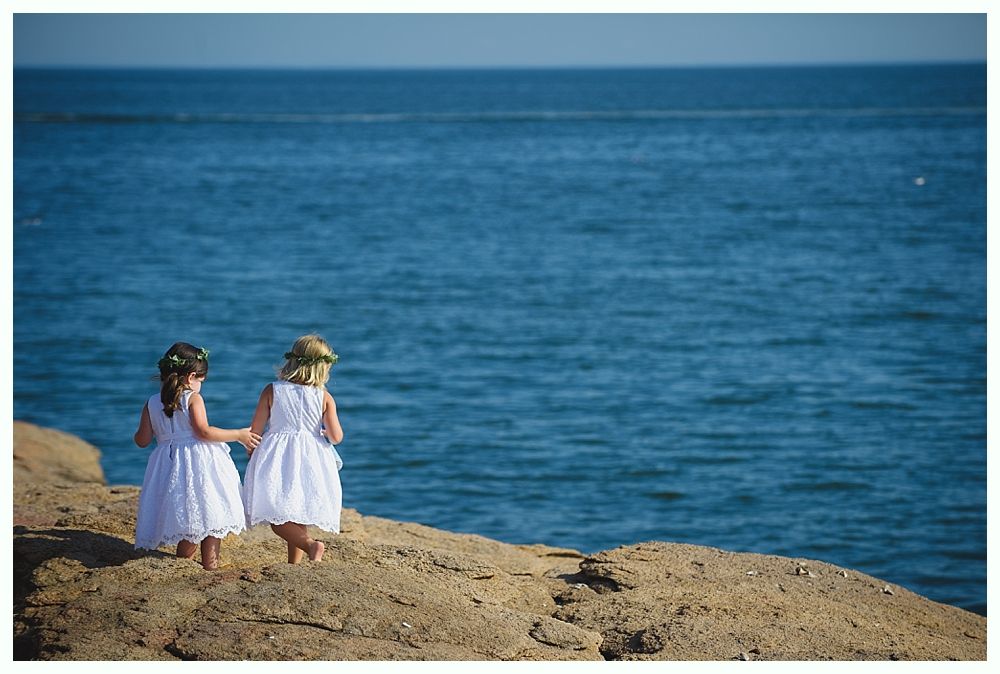 Bride with arms up, making a funny face, groom looking at his hand, cake cutting in background.