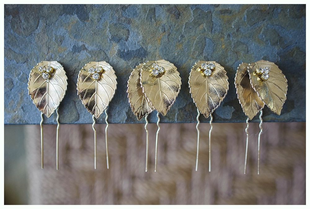 Wedding party on a beach with blue sky. Bride and groom embrace, others stand nearby. Dark blue dresses and jackets.