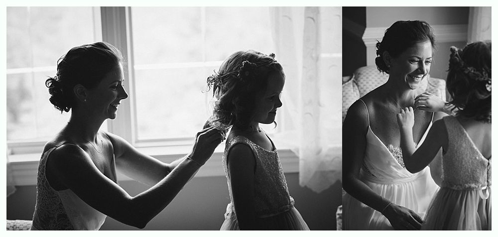 Bride with arms up, making a funny face, groom looking at his hand, cake cutting in background.