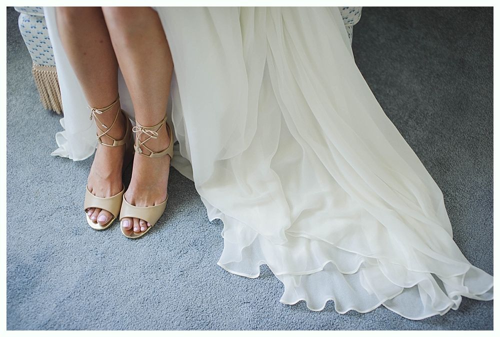 Bride with arms up, making a funny face, groom looking at his hand, cake cutting in background.