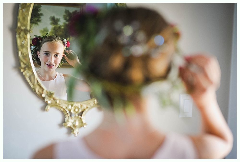 Bride with arms up, making a funny face, groom looking at his hand, cake cutting in background.