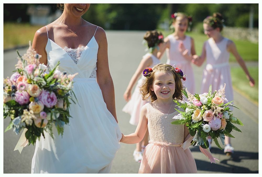Bride with arms up, making a funny face, groom looking at his hand, cake cutting in background.