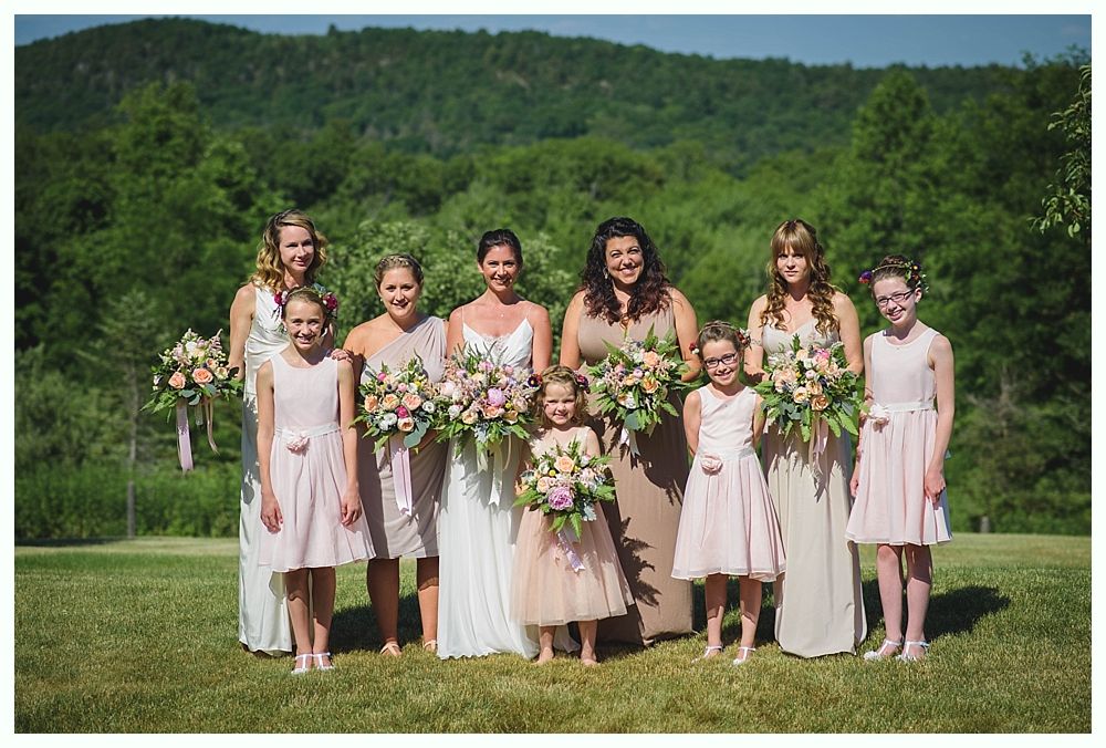 Bride with arms up, making a funny face, groom looking at his hand, cake cutting in background.