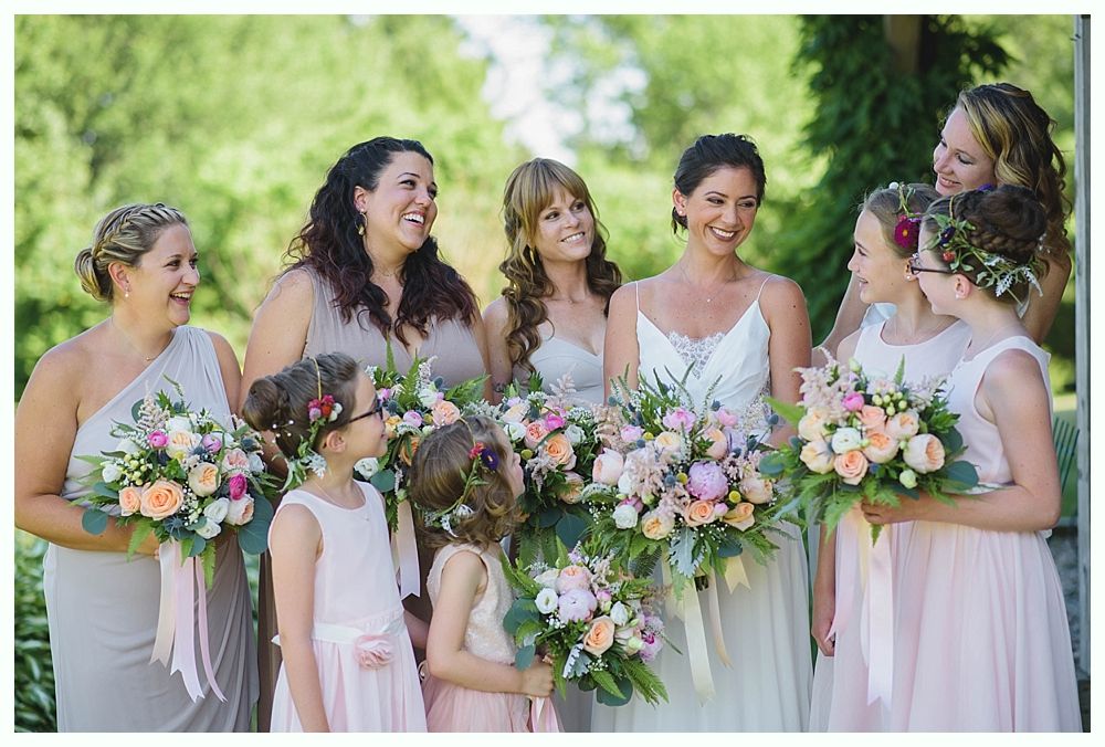 Bride with arms up, making a funny face, groom looking at his hand, cake cutting in background.
