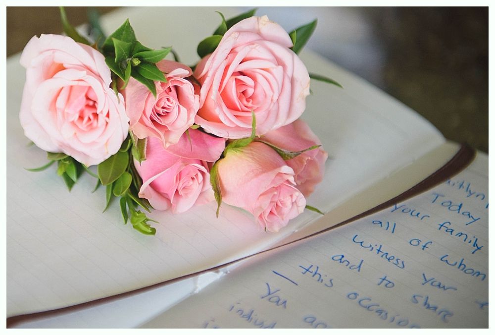 Bride with arms up, making a funny face, groom looking at his hand, cake cutting in background.