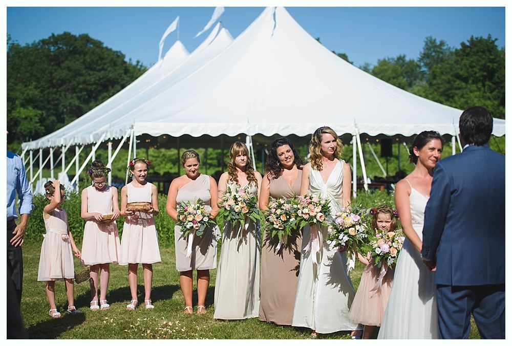 Bride with arms up, making a funny face, groom looking at his hand, cake cutting in background.