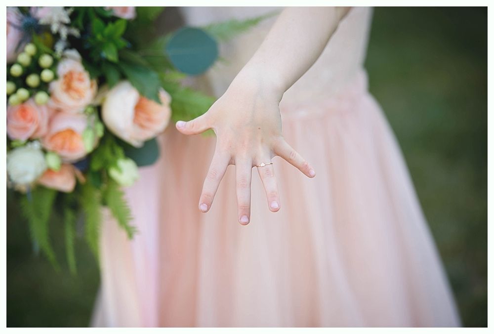 Bride with arms up, making a funny face, groom looking at his hand, cake cutting in background.