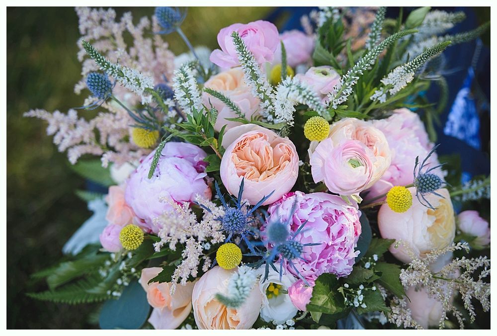 Bride with arms up, making a funny face, groom looking at his hand, cake cutting in background.