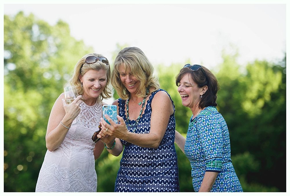 Bride with arms up, making a funny face, groom looking at his hand, cake cutting in background.