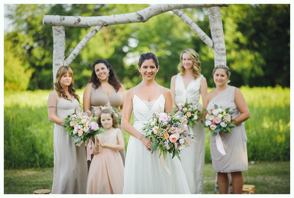 Bride with arms up, making a funny face, groom looking at his hand, cake cutting in background.