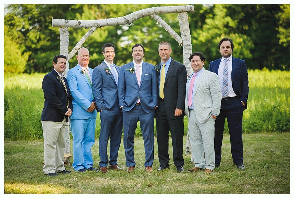 Bride with arms up, making a funny face, groom looking at his hand, cake cutting in background.