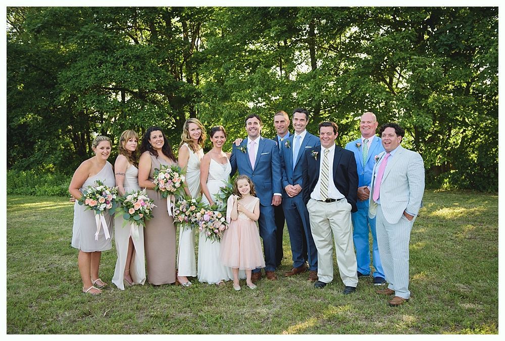 Bride with arms up, making a funny face, groom looking at his hand, cake cutting in background.
