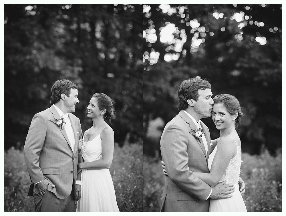 Bride with arms up, making a funny face, groom looking at his hand, cake cutting in background.