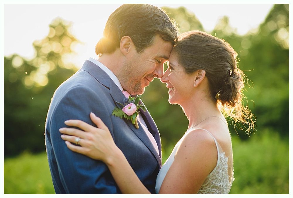 Bride with arms up, making a funny face, groom looking at his hand, cake cutting in background.