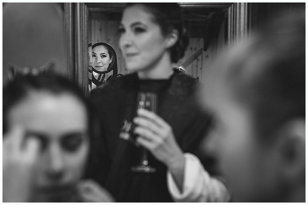 Woman holding a glass, smiling. Another woman is visible in the background, also smiling. Black and white.