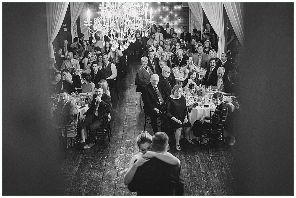 Newlyweds embrace on a dance floor, surrounded by guests at a wedding reception.