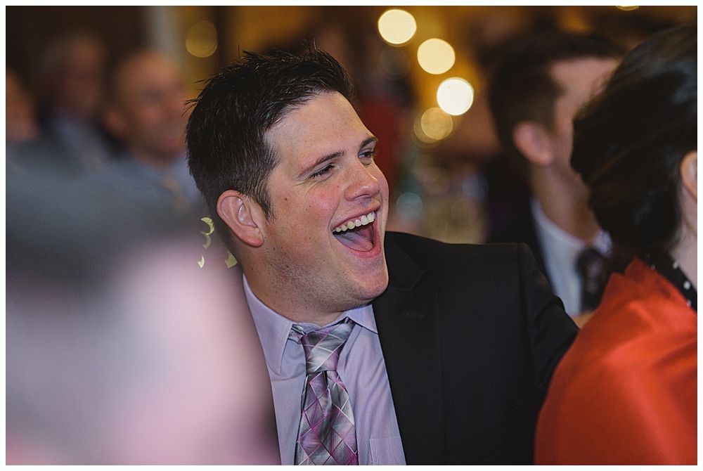 Man in suit laughing with mouth wide open at an event.