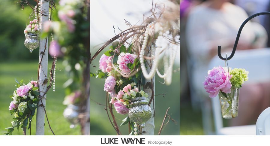 Floral decorations on a birch archway, including pink flowers in glass jars.