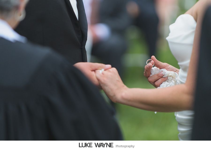 Bride and groom exchanging rings during outdoor wedding ceremony.