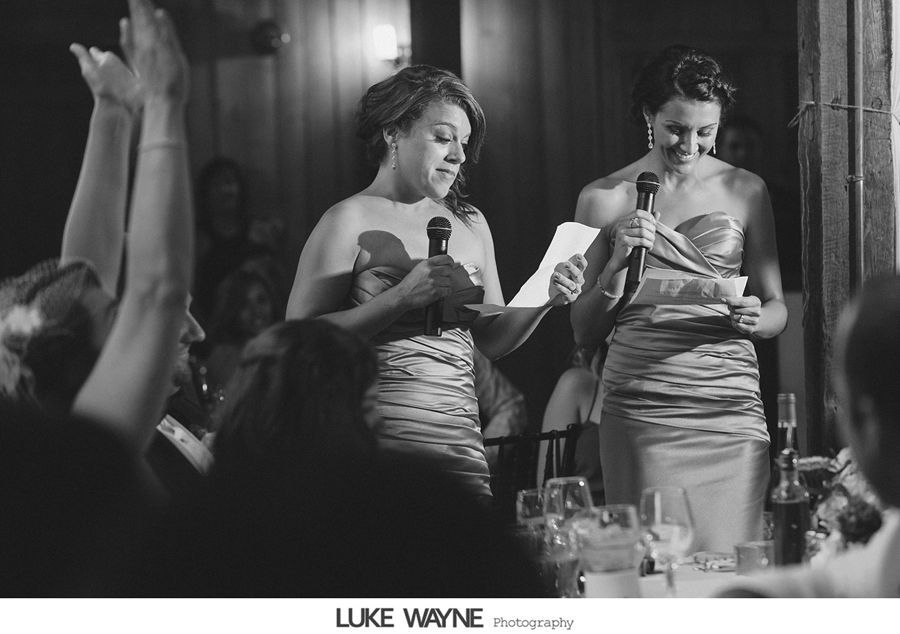 Two women in strapless dresses giving speeches at a wedding reception.