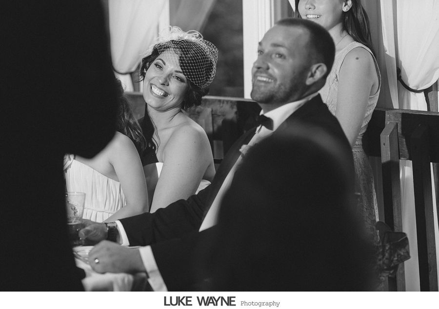 Bride and groom laughing at a wedding reception table. Black and white.