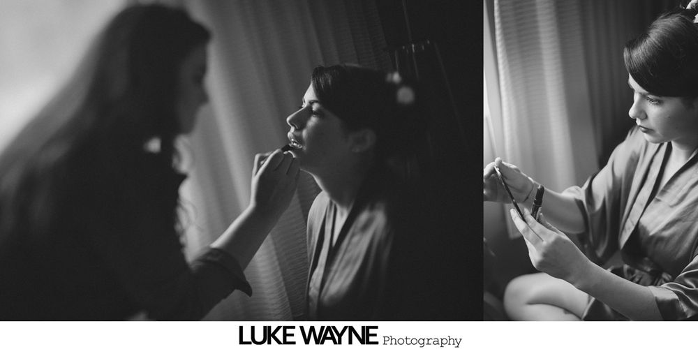 Woman in teal dress helping another woman fasten her white wedding dress.