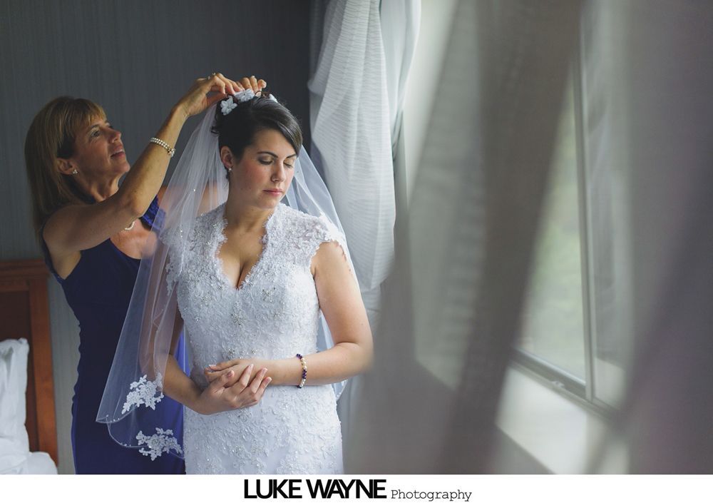 Couple in wedding attire walk through a sunny orchard.