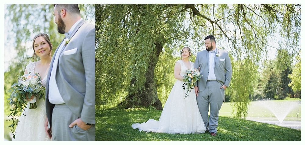 Bride and groom pose outdoors in front of a tree. The couple is smiling and holding flowers.
