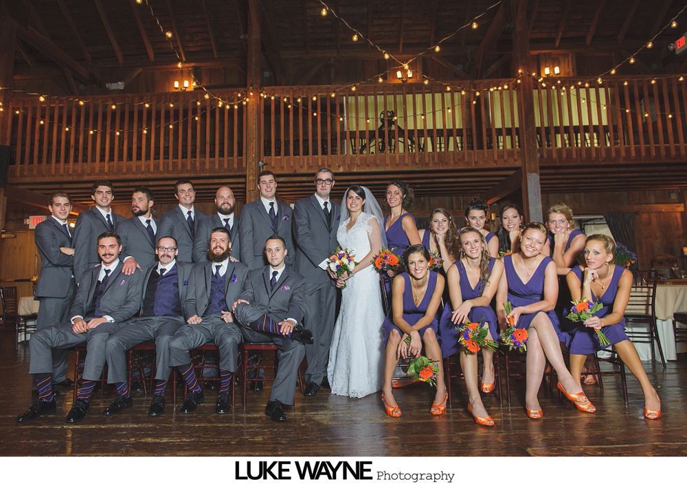 Bride in a white dress with bridesmaids in teal dresses on a grassy field on a sunny day.