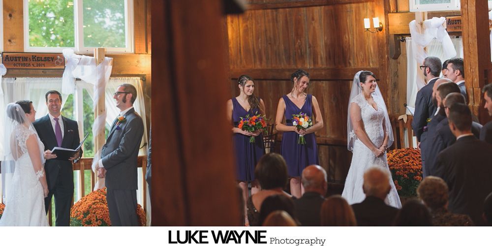 Wedding party in front of a red barn, the wedding party in black suits and teal dresses with fall foliage backdrop.