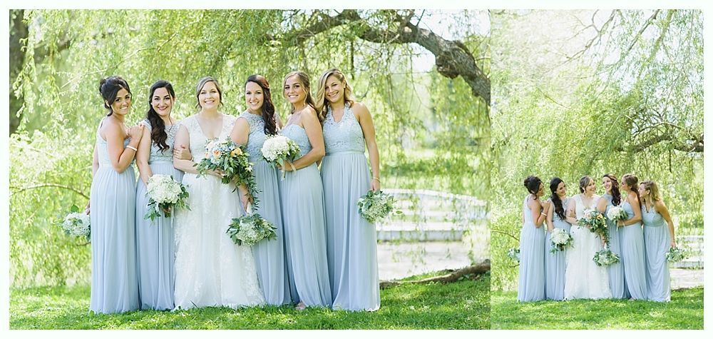 Bride and bridesmaids in blue dresses pose under a weeping willow.