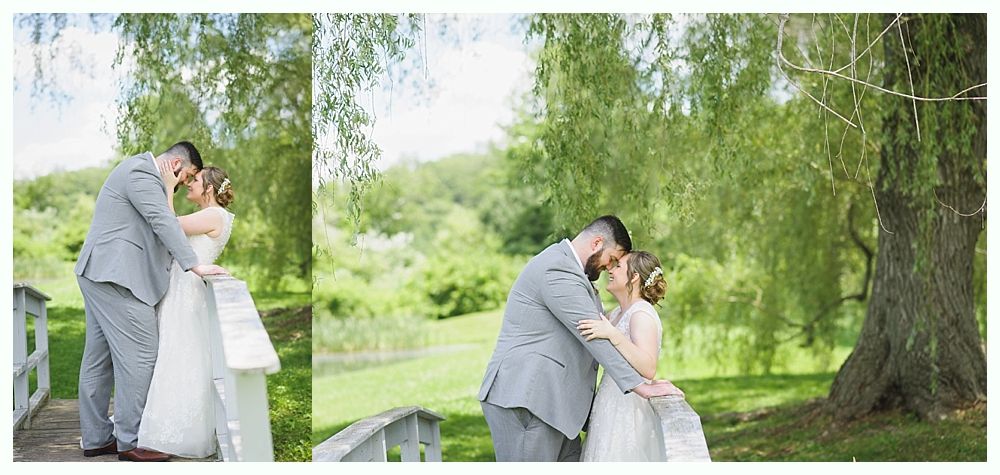 A couple embraces on a bridge in front of a tree during a wedding. They are near each other.