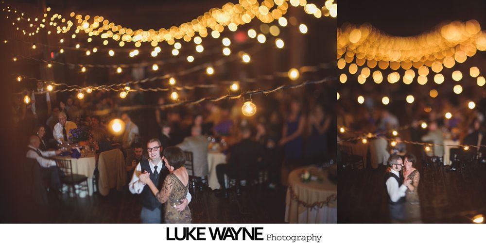 Two men embrace on a dance floor at a wedding reception.