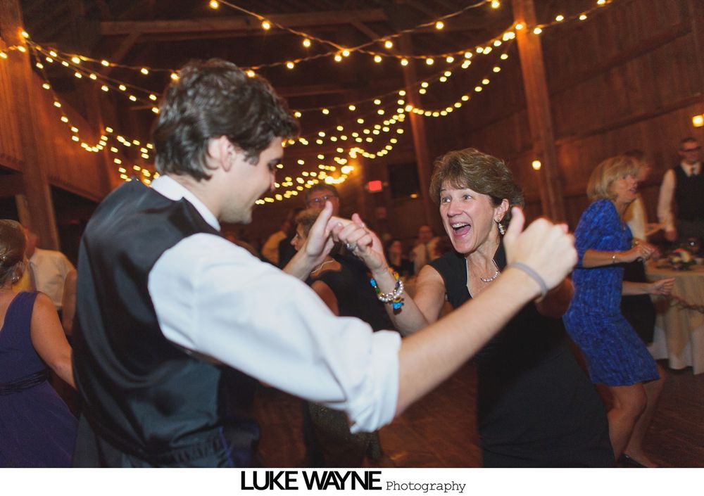 Wedding reception with dancing; bride in a white gown and guests in colorful dresses on a dance floor.