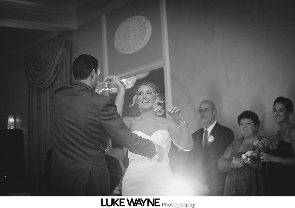 Bride and groom toasting with champagne; guests watch.