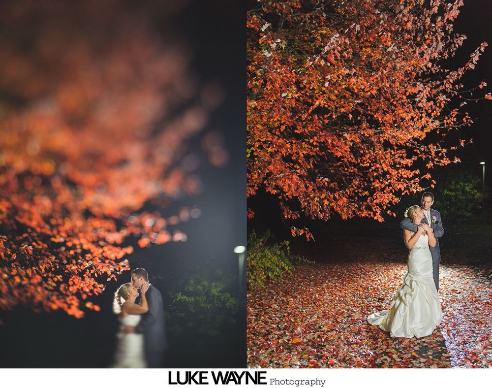 Bride and groom under a tree with orange leaves at night.