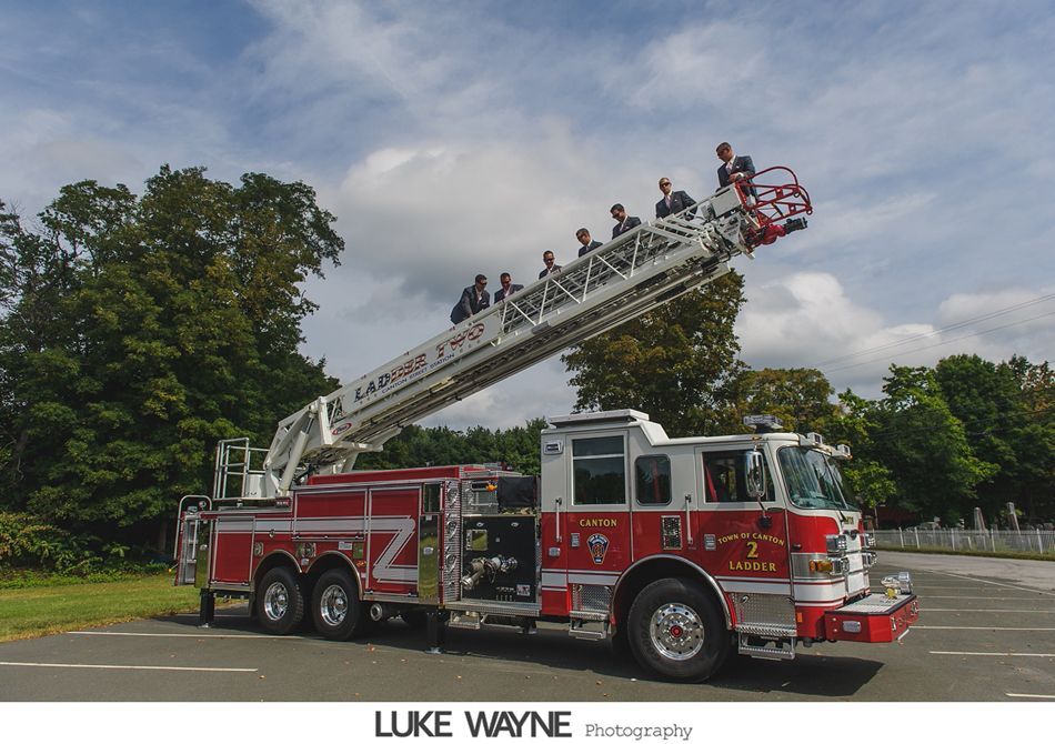 Fire truck with extended ladder holding people. Cloudy sky.
